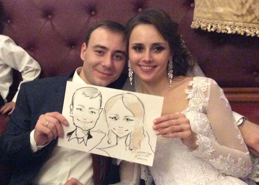 Илья и Маша держат свой свадебный шарж от Михаила Шабалина