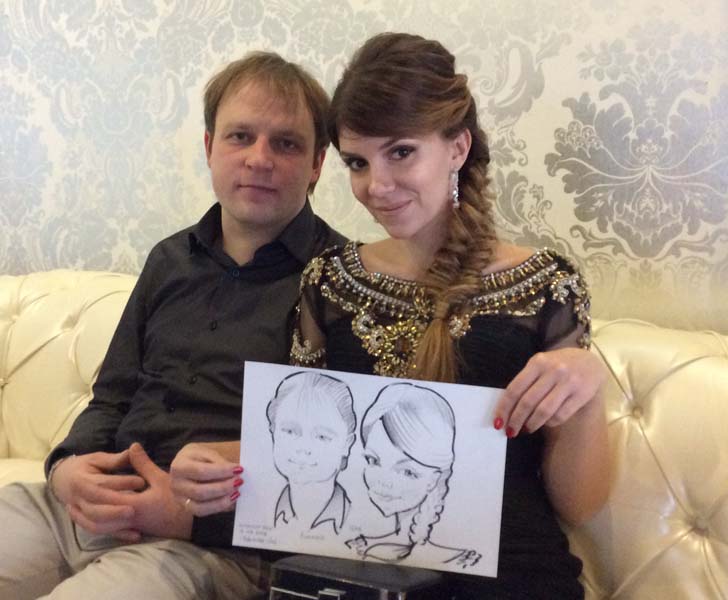 Алексей и Юля держат свой шарж на свадьбе в 