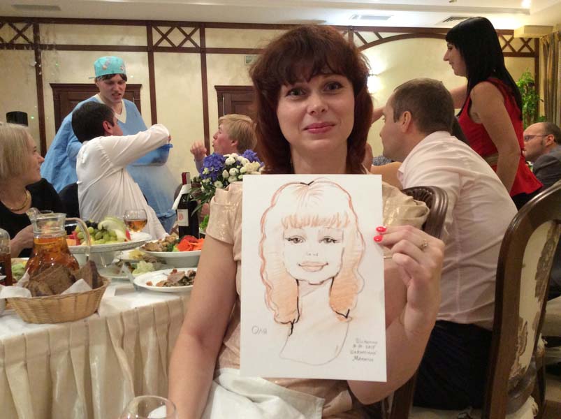 Оля демонстрирует свой шарж от шаржиста Мишеля на свадьбе